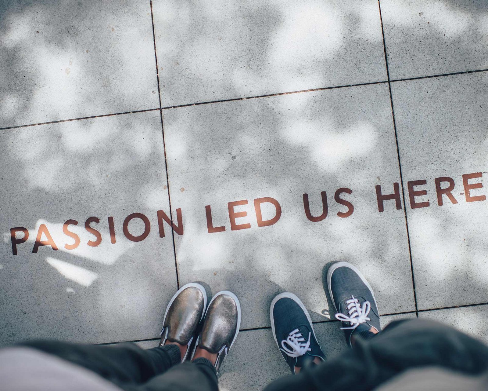 Schriftzug „Passion led us here“ auf dem Boden vor zwei Paar Schuhen