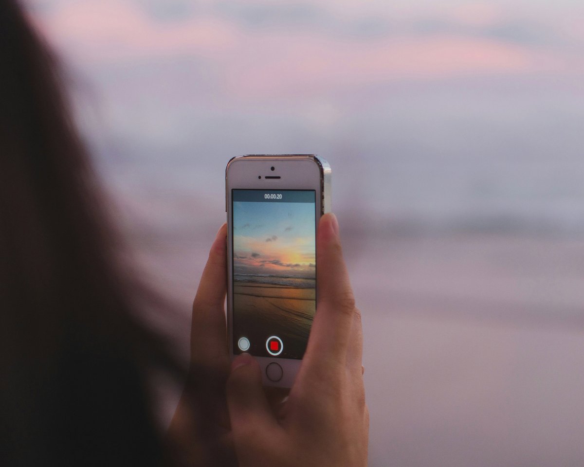 Smartphone filmt einen Sonnenuntergang am Meer