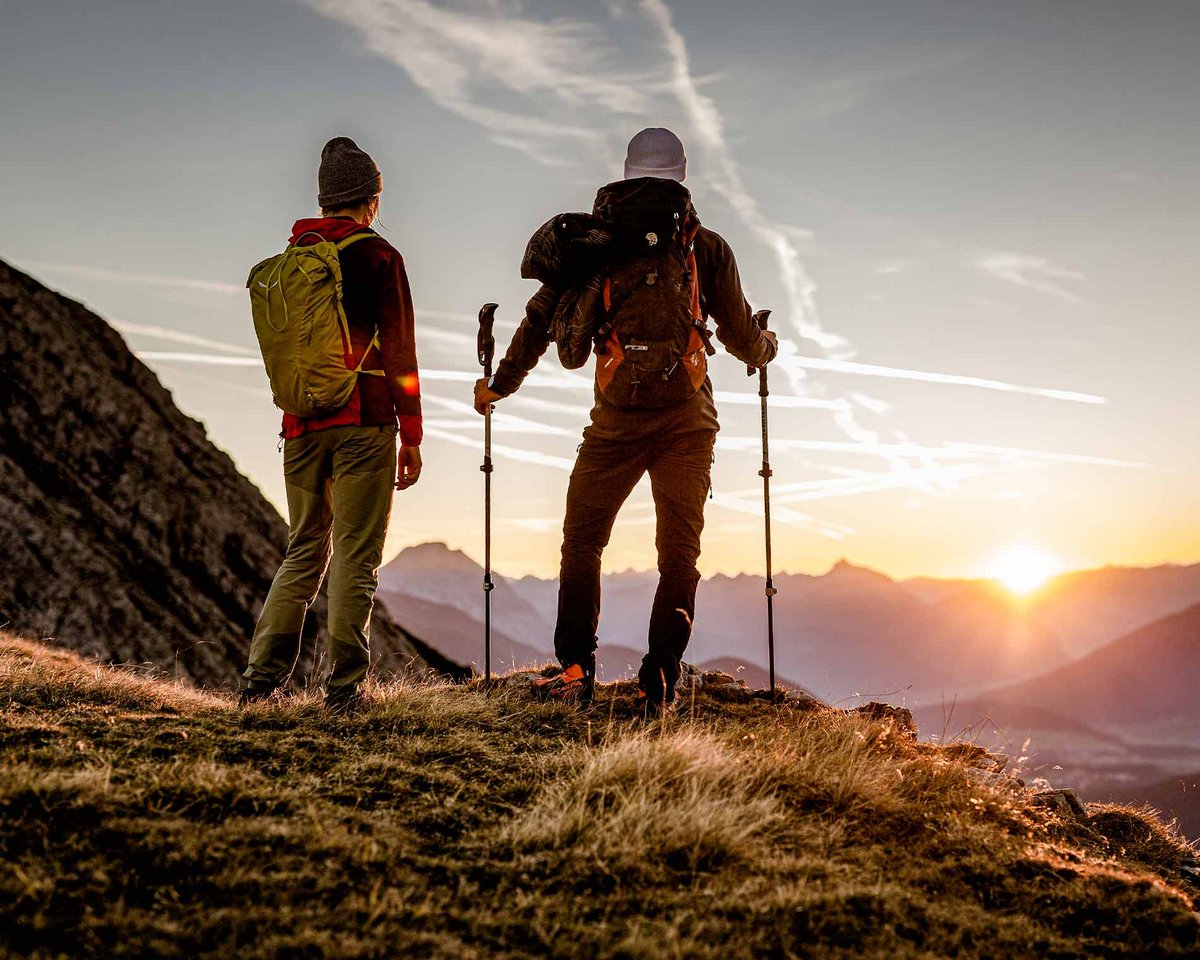Zwei Wanderer bei Sonnenaufgang auf einem Gipfel bei Imst
